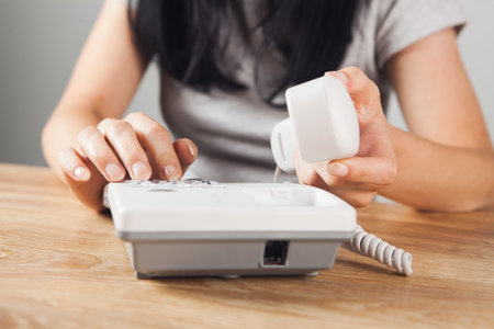 woman calls home wired phoneの写真素材