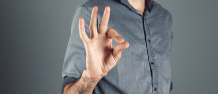 man shows ok on gray backgroundの写真素材