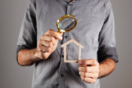 man holding a house and a magnifying glass. home search conceptの写真素材