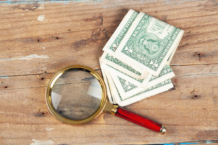 a magnifying glass and a banknote on the tableの写真素材