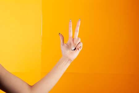 woman with fingers shows three on orange backgroundの写真素材