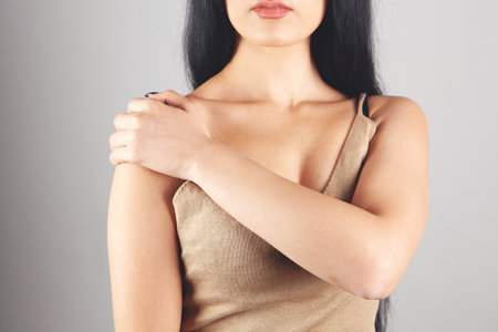a woman has a sore shoulder on a gray backgroundの写真素材