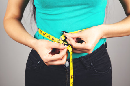 young woman measuring belly with tapeの写真素材