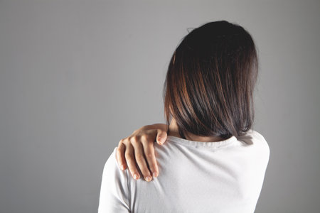 woman has shoulder pain on gray backgroundの写真素材