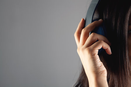 young woman stands in large headphones on a gray backgroundの写真素材