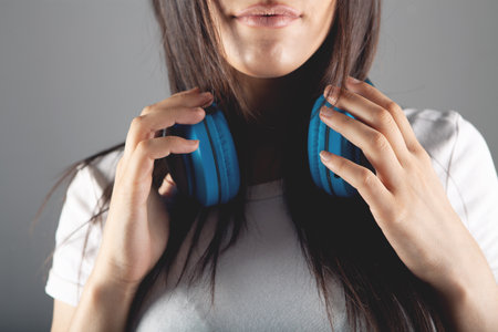 young woman stands in large headphones on a gray backgroundの写真素材