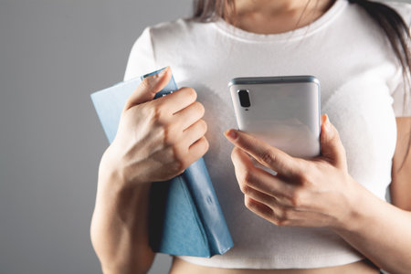 young woman stands with a book and holds a phoneの写真素材