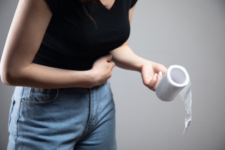 woman stands with toilet paper and stomach painの写真素材