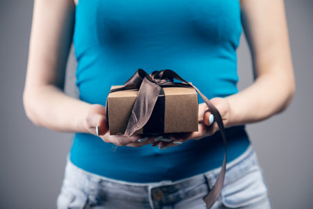 Young girl with gift box on gray backgroundの写真素材
