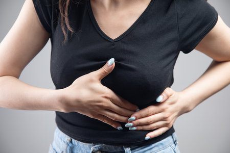 a young woman has a chest pain on a gray backgroundの写真素材