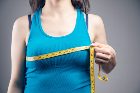 young woman measures her bust with a measuring tape