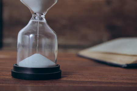 open book and hourglass on a wooden table