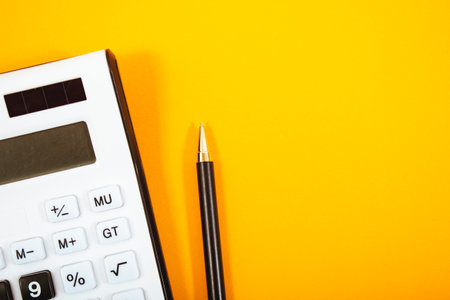 calculator and pen on orange backgroundの写真素材