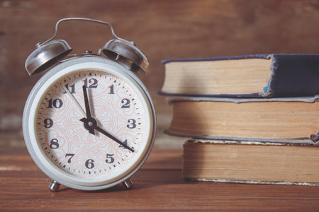 alarm clock and books on a wooden tableの写真素材