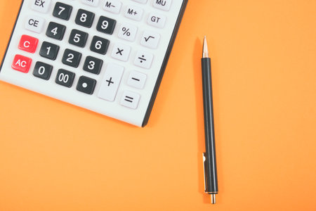 calculator and pen on orange background