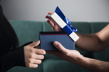 a man gives a gift to a woman sitting on a couch. the concept of a family holiday