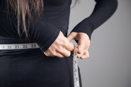 Young woman measuring abdominal circumference with measuring tapeの写真素材