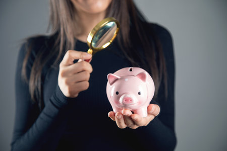 woman looking at a piggy bank with a magnifying glassの写真素材