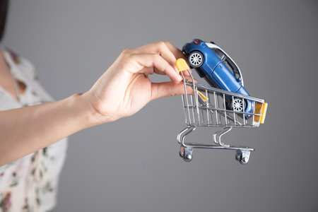 buying a car. woman holding trolley by carの写真素材