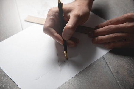 a man takes measurements on paper with a ruler and pencil