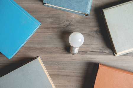 books and a light bulb on the tableの写真素材