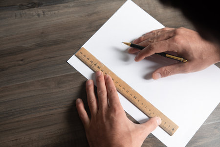 a man takes measurements on paper with a ruler and pencilの写真素材