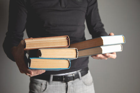man holding books in his hands on gray background