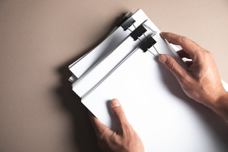 a man holding a stack of papers on the tableの写真素材