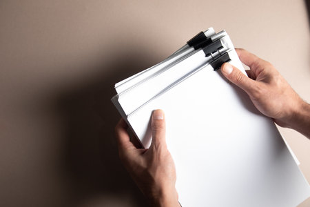 a man holding a stack of papers on the tableの写真素材