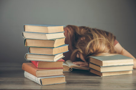 young woyoung woman fell asleep while sitting in front of booksの写真素材