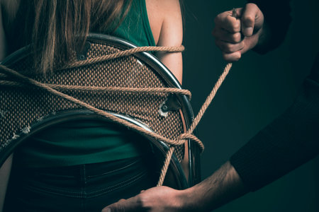 a man ties a woman to a chair with a ropeの写真素材