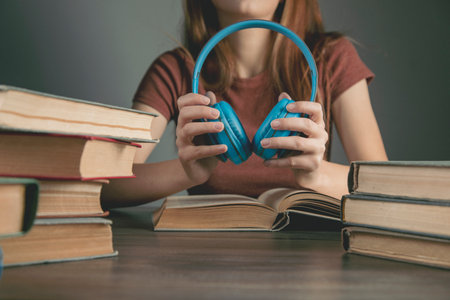 woman holds headphones while sitting in front of books. audiobook conceptの写真素材