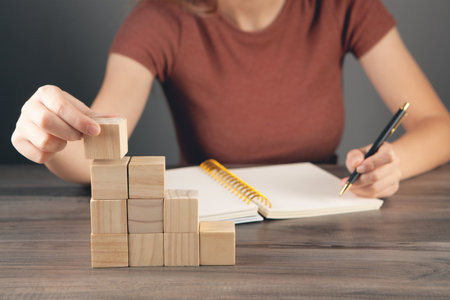 woman makes notes in a notebook and holds a ladder of cubesの写真素材