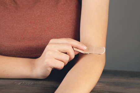 young girl puts on a bandage on her arm