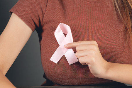 woman holding a pink ribbon at her chestの写真素材