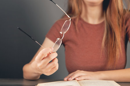 woman holding glasses in front of a bookの写真素材