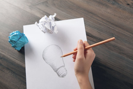 woman draws a light bulb on paperの写真素材