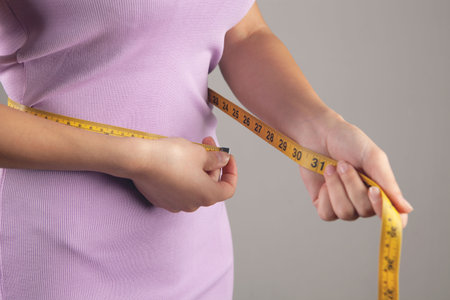 Young woman measuring abdominal circumference with measuring tapeの写真素材