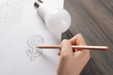 woman draws a dollar sign on paper and next to a light bulb