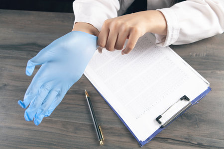 the doctor puts on a glove in front of the work tableの写真素材