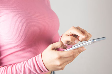 young woman presses the phone screen on a gray backgroundの写真素材