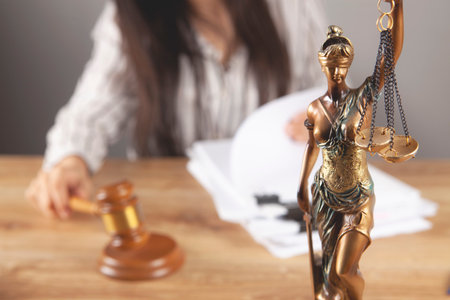 the judge sits in front of the gavel and the statue of justiceの写真素材