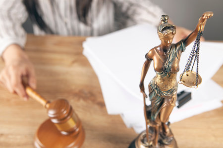 the judge sits in front of the gavel and the statue of justiceの写真素材