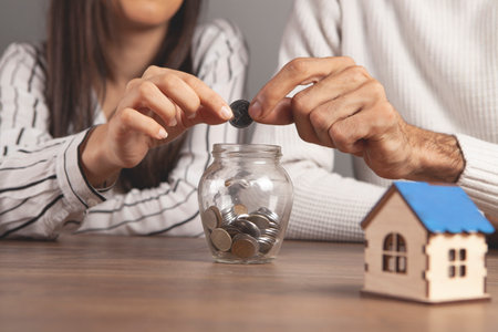 a man and a woman throw coins into a piggy bank at homeの写真素材