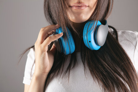 young woman stands in large headphones on a gray backgroundの写真素材