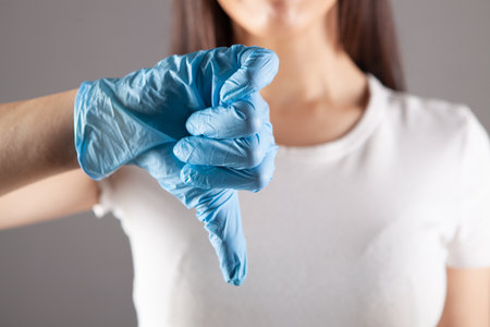 young woman in medical glove shows thumb downの写真素材