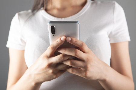 young woman presses the phone screen on a gray backgroundの写真素材