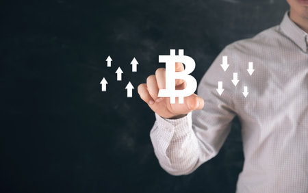Bitcoin icon with up and down arrows. Man tapping on the screenの写真素材