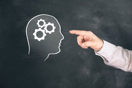 The illustrated human head has a gear. Man tapping on the screen