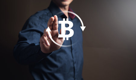 Bitcoin icon in a circle. Man tapping on the screenの写真素材